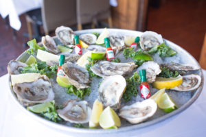 A plate of Oysters with ice, Lemon slices and Tabasco hot sauce
