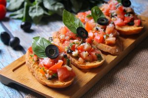 alt="several pieces of bread with olives and tomatoes on them"